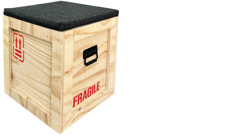 Holzhocker im Übersee-Transportkisten-Look mit FRAGILE-Aufdruck und schwarzem Sitzkissen zum Mieten